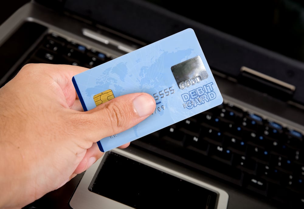 credit card over a computer keyboard held by hand - note the design of the card is my own