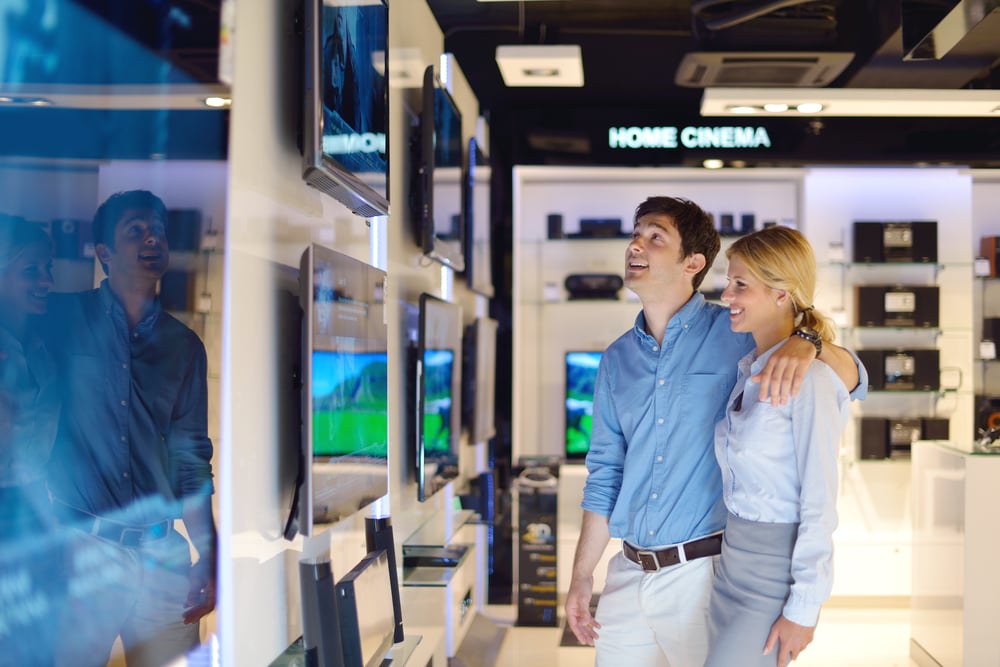 Menschen im Einzelhandelsgeschäft für Unterhaltungselektronik schauen sich die neuesten Laptops, Fernseher und Fotokameras zum Kauf an