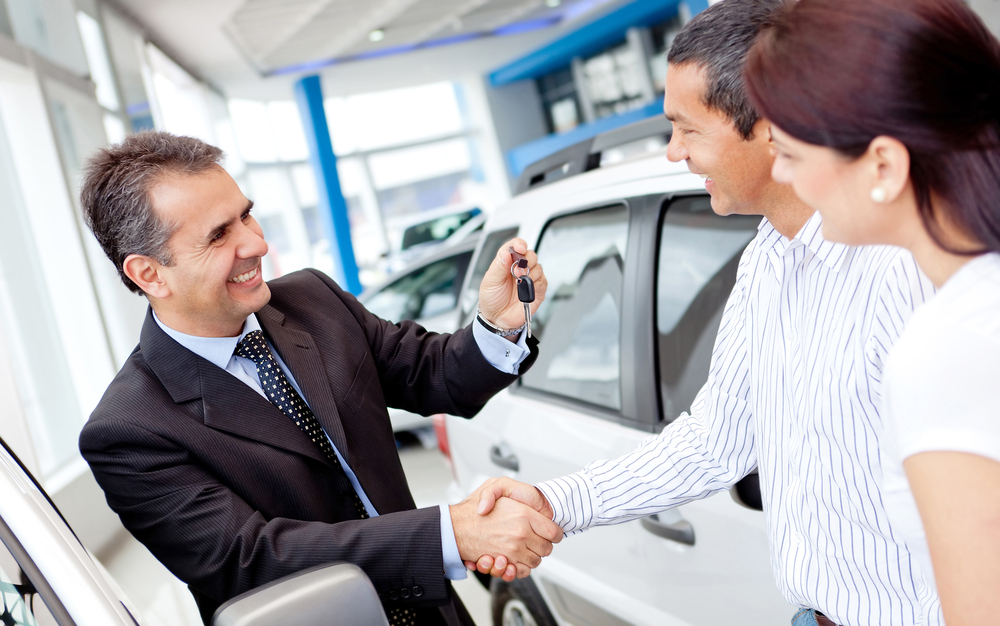 Paar kauft ein Auto und Verkäufer kümmert sich um Schlüssel